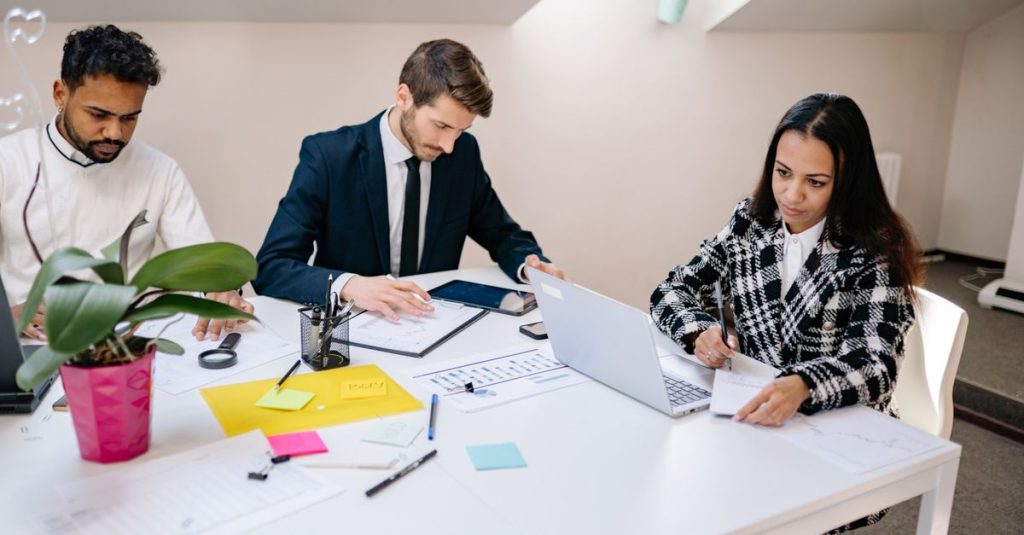 A digital marketing team collaborating around a table with a laptop displaying SEO data